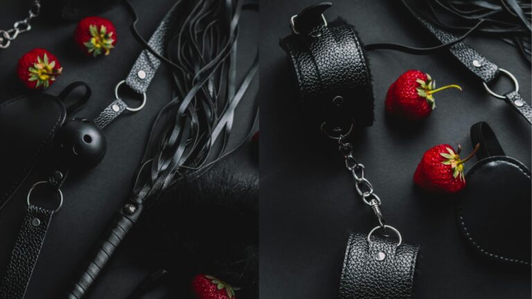 Leather BDSM restraints, whips, and fresh red strawberries arranged on a dark surface.